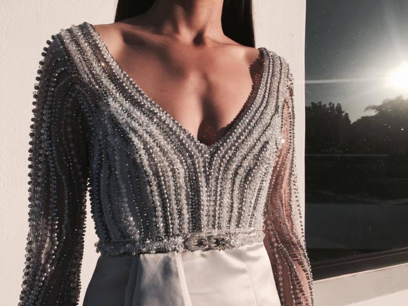 Close detail of a beaded long-sleeve bodice with a plunging neckline