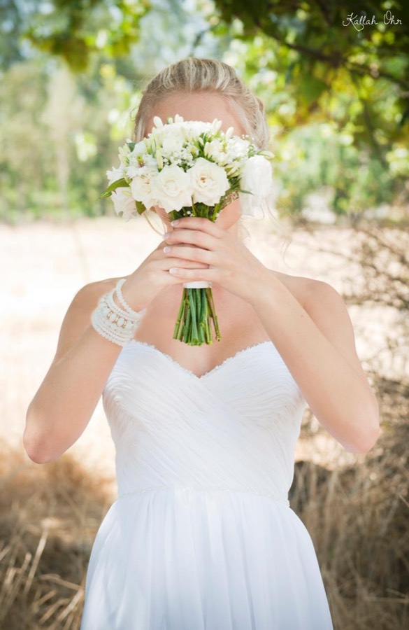 Bride holding her bouquet, lace sleeve and sweetheart bodice in frame