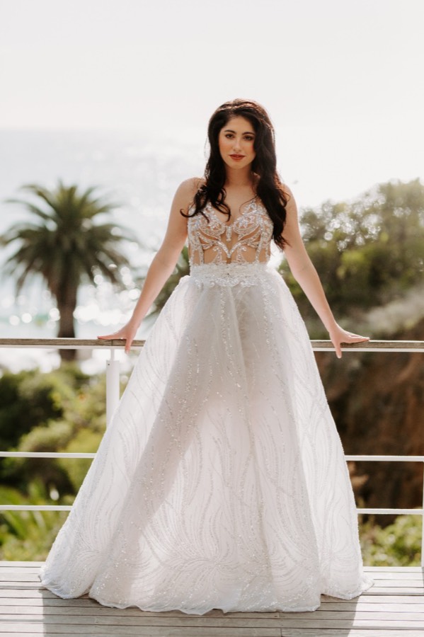 Bride beneath palms in a lace gown with a fitted bodice