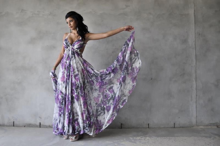The same floral chiffon gown held open against a concrete wall