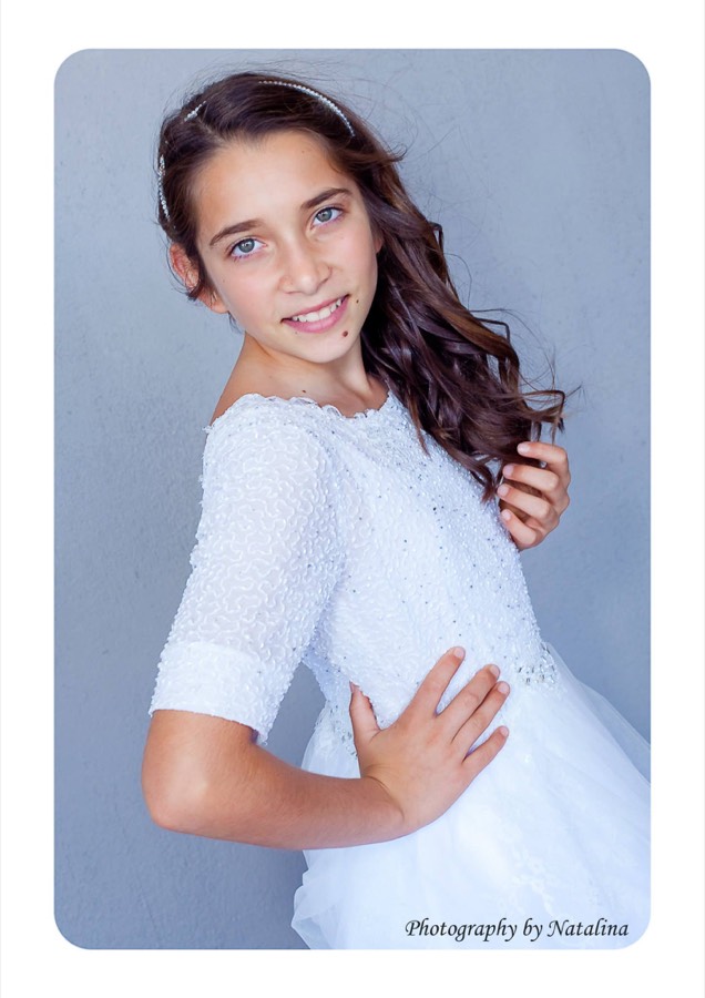 Young girl in a white communion dress with a lace-trimmed bodice